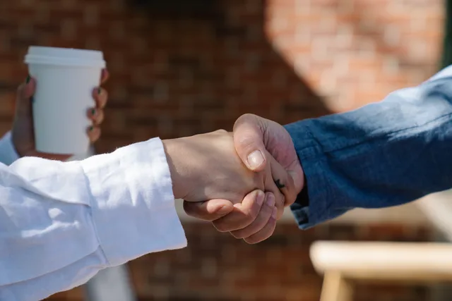 Close-up of a handshake between two adults, symbolizing agreement or partnership. Sådan vurderer du forretningsbeskrivelsen i en profil